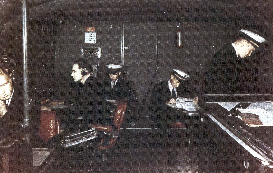 Boeing B314 Rear of cockpit.  Navigator, extreme left, Flight Engineer on left with headphones, reserve officers center rear at planning tables, Navigator or right next to plotting table